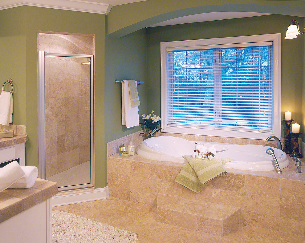 This is an example of a large beach style master bathroom in Miami with raised-panel cabinets, white cabinets, tile benchtops, a drop-in tub, a corner shower, beige tile, stone tile, green walls and travertine floors.