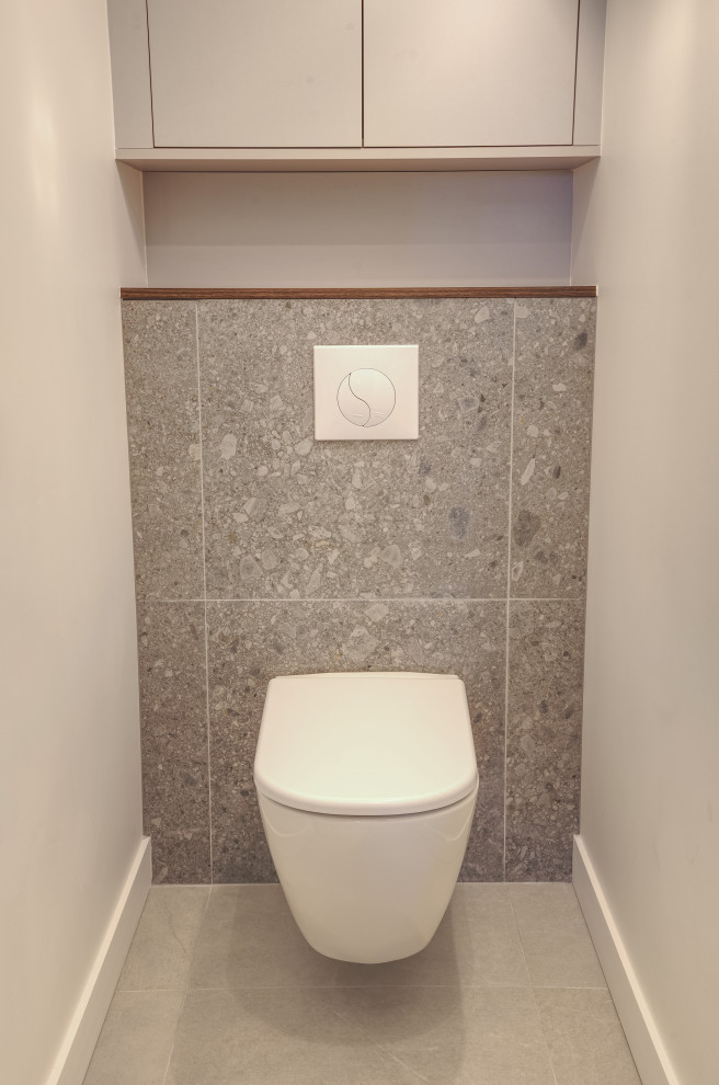 Idées déco pour un grand WC suspendu moderne avec un placard à porte affleurante, des portes de placard grises, un carrelage gris, des carreaux de céramique, un mur blanc, un sol en carrelage de céramique, un plan de toilette en bois, un sol gris, un plan de toilette marron et meuble-lavabo encastré.