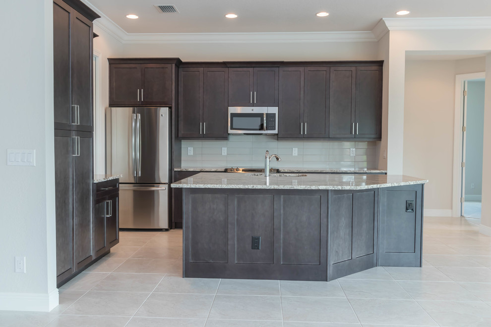 Inspiration for a mid-sized contemporary l-shaped porcelain tile and beige floor open concept kitchen remodel with an undermount sink, shaker cabinets, dark wood cabinets, granite countertops, gray backsplash, porcelain backsplash, stainless steel appliances and an island