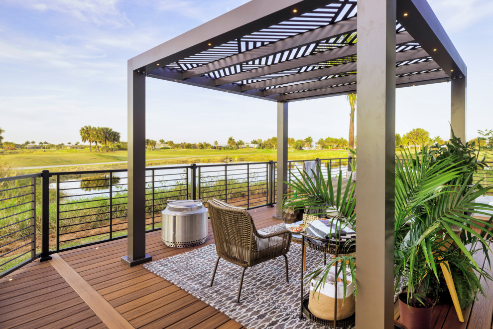 Immagine di una terrazza tropicale dietro casa e a piano terra con una pergola e parapetto in metallo
