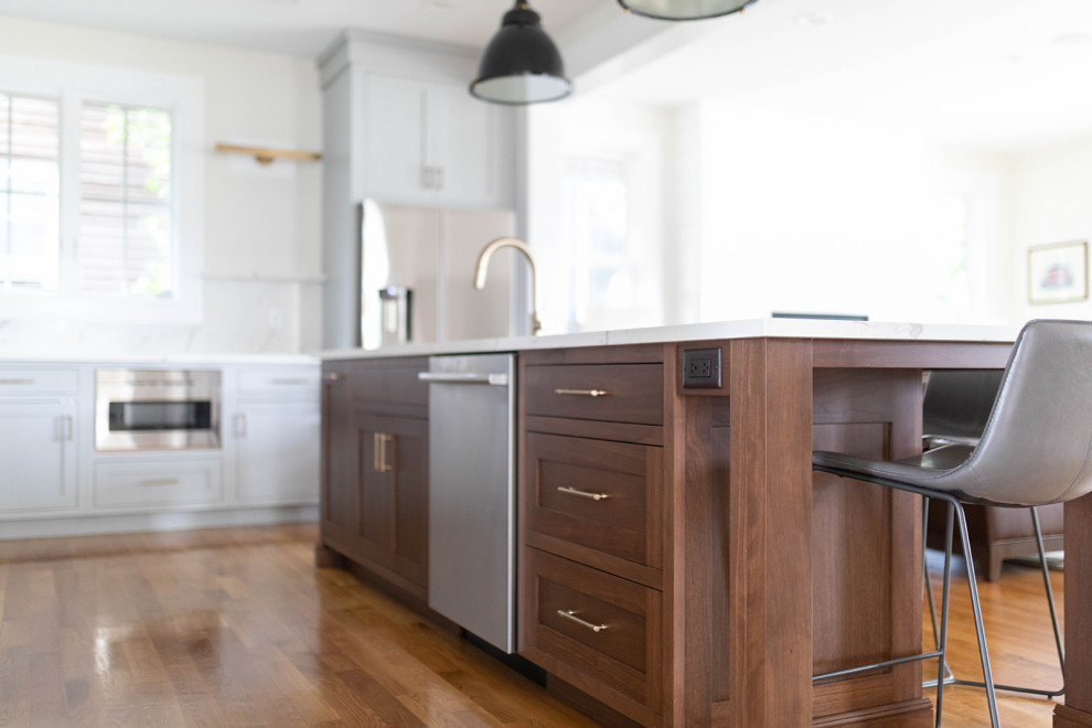 Photo of a medium sized classic kitchen in New York with a submerged sink, shaker cabinets, dark wood cabinets, engineered stone countertops, white splashback, engineered quartz splashback, medium hardwood flooring, an island, brown floors and white worktops.