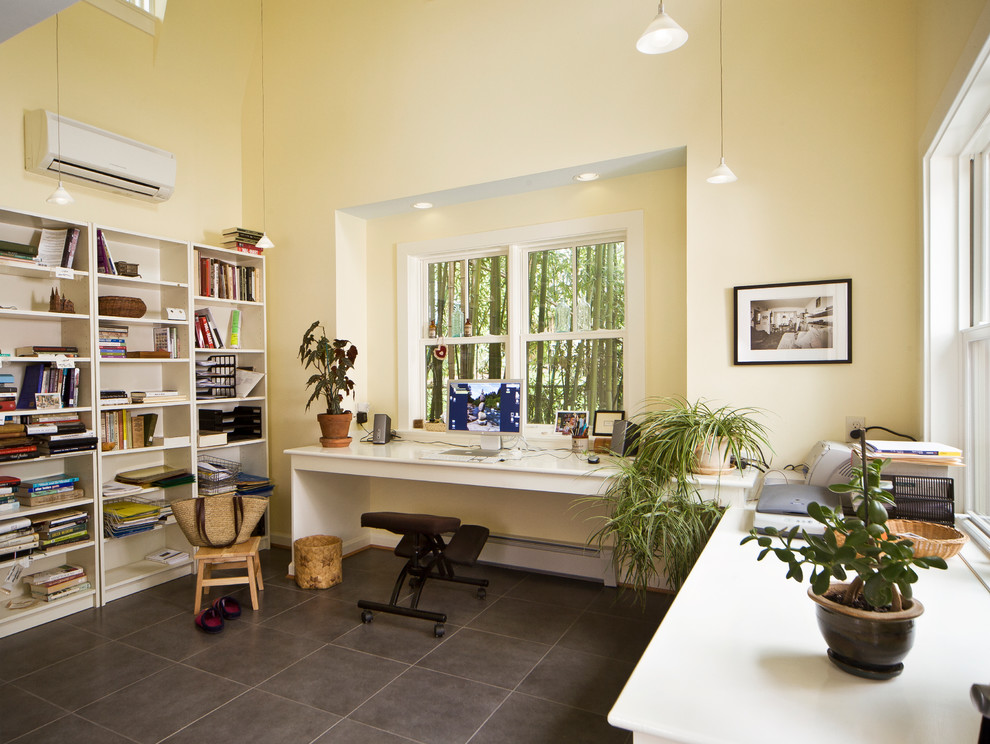 This is an example of a mid-sized traditional home office in DC Metro with yellow walls, a built-in desk, porcelain floors, no fireplace and grey floor.
