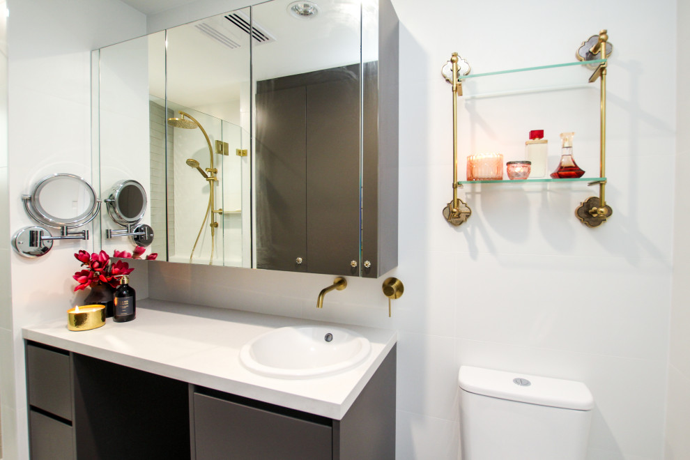 This is an example of a mid-sized eclectic 3/4 bathroom in Sydney with grey cabinets, white tile, white walls, a hinged shower door, white benchtops and a single vanity.
