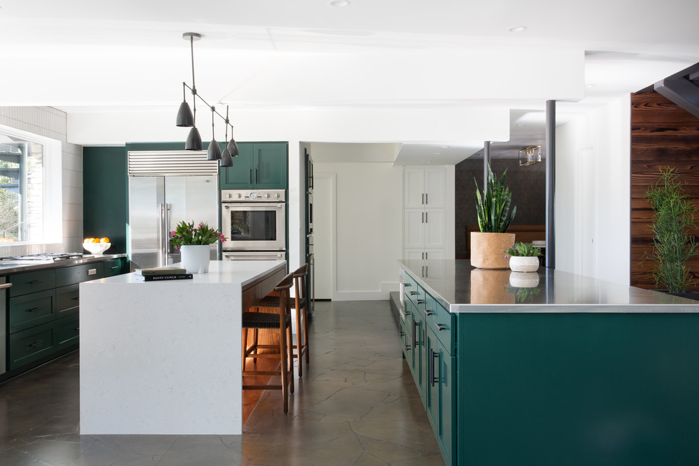 Photo of a large contemporary u-shaped open plan kitchen in Austin with an integrated sink, recessed-panel cabinets, green cabinets, quartzite benchtops, white splashback, ceramic splashback, stainless steel appliances, limestone floors, brown floor, white benchtop and multiple islands.