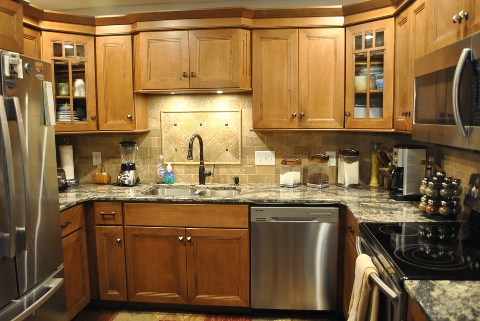 Kitchen - brown floor kitchen idea with brown cabinets, beige backsplash, stainless steel appliances, an island and gray countertops