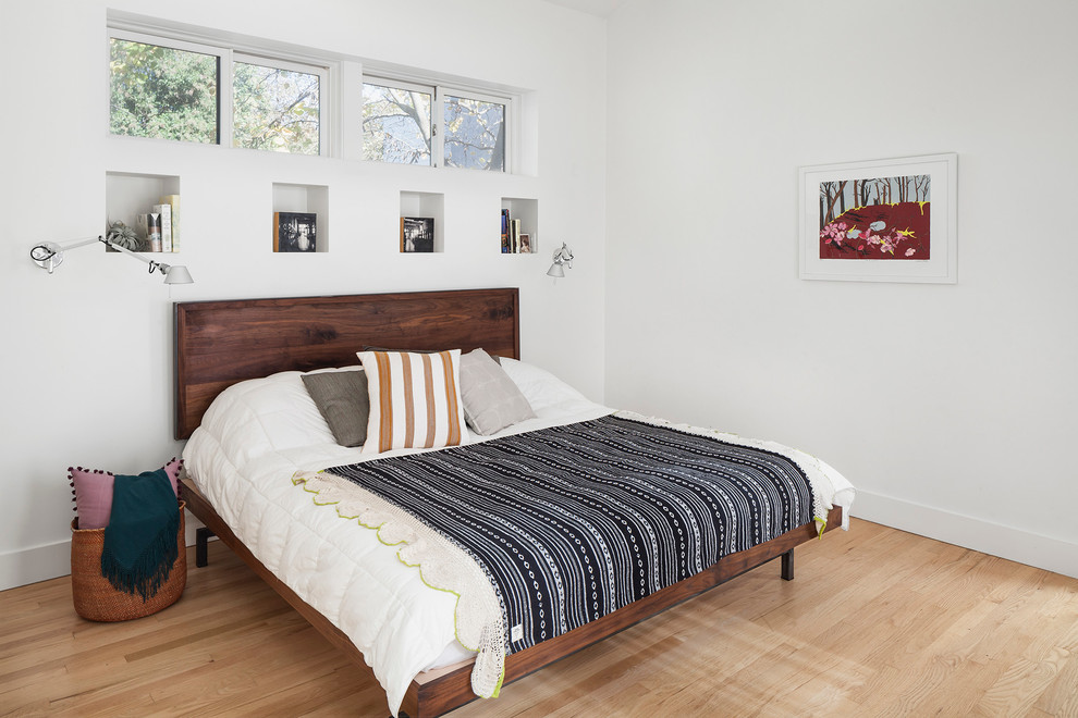 This is an example of a mid-sized scandinavian master bedroom in Austin with white walls, light hardwood floors and no fireplace.