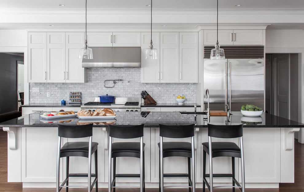 Design ideas for a mid-sized transitional galley open plan kitchen in Boston with white cabinets, grey splashback, stone tile splashback, stainless steel appliances, with island, shaker cabinets and dark hardwood floors.