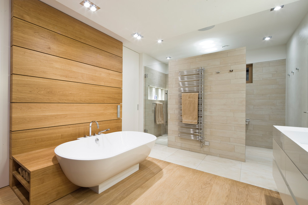 Contemporary master bathroom in Dusseldorf with flat-panel cabinets, white cabinets, a freestanding tub, an open shower, beige tile, white walls, light hardwood floors, an integrated sink and a hinged shower door.