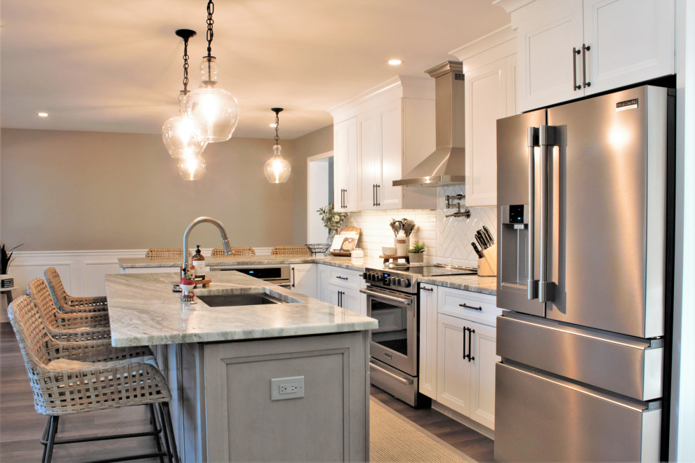 Bild på ett mellanstort vintage grå grått kök, med en undermonterad diskho, luckor med infälld panel, vita skåp, bänkskiva i kvarts, vitt stänkskydd, stänkskydd i tunnelbanekakel, rostfria vitvaror, ljust trägolv, en köksö och brunt golv