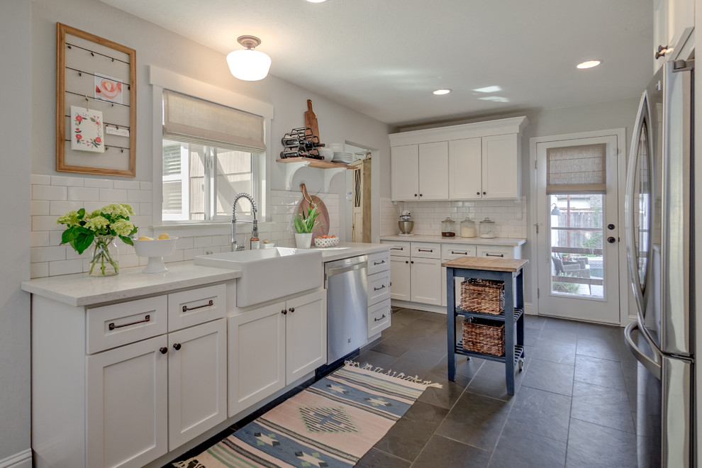 Photo of a country u-shaped separate kitchen in Sacramento with a farmhouse sink, shaker cabinets, white cabinets, white splashback, subway tile splashback, with island and grey floor.