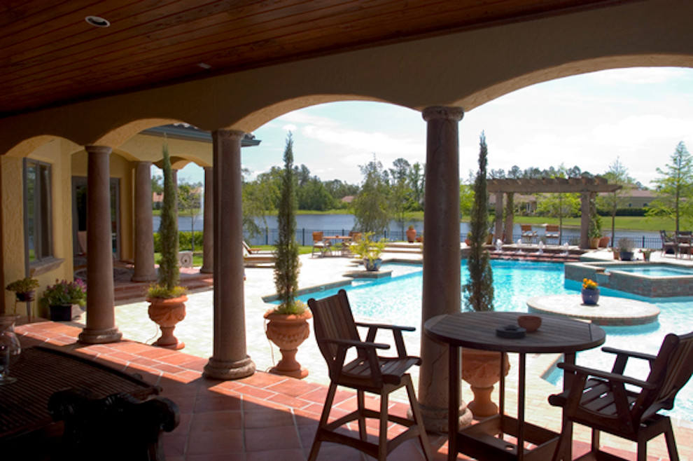 This is an example of a large mediterranean backyard patio in Orlando with a water feature and an awning.