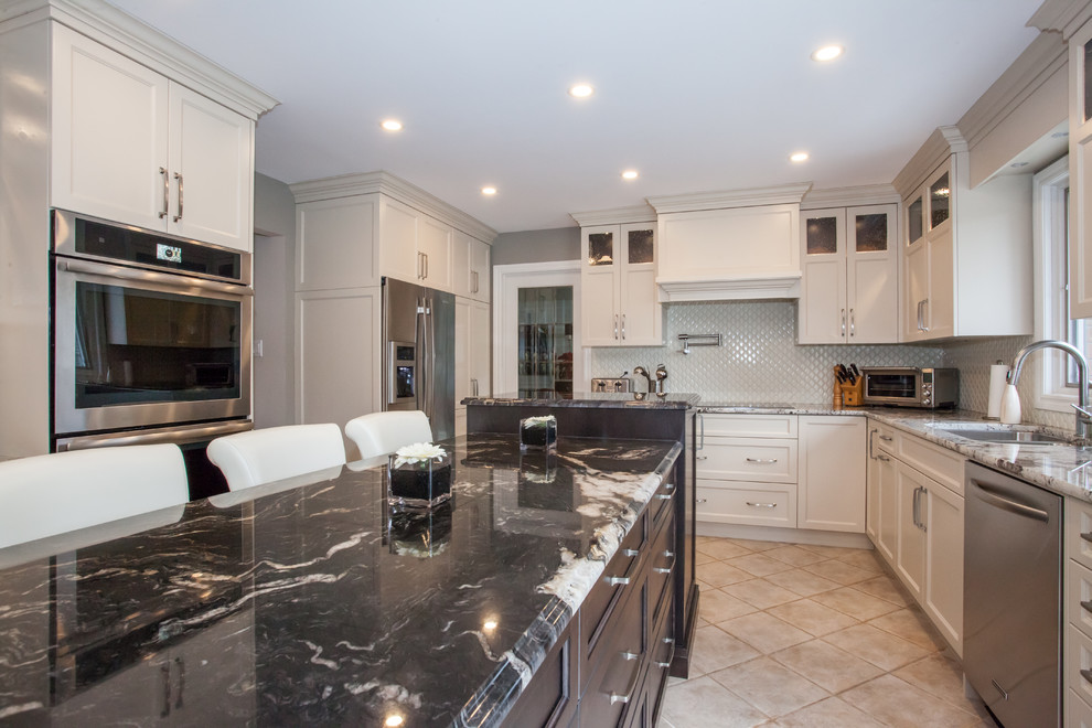 Large traditional u-shaped eat-in kitchen in Toronto with an undermount sink, recessed-panel cabinets, white cabinets, granite benchtops, white splashback, ceramic splashback, stainless steel appliances, ceramic floors, with island, beige floor and multi-coloured benchtop.
