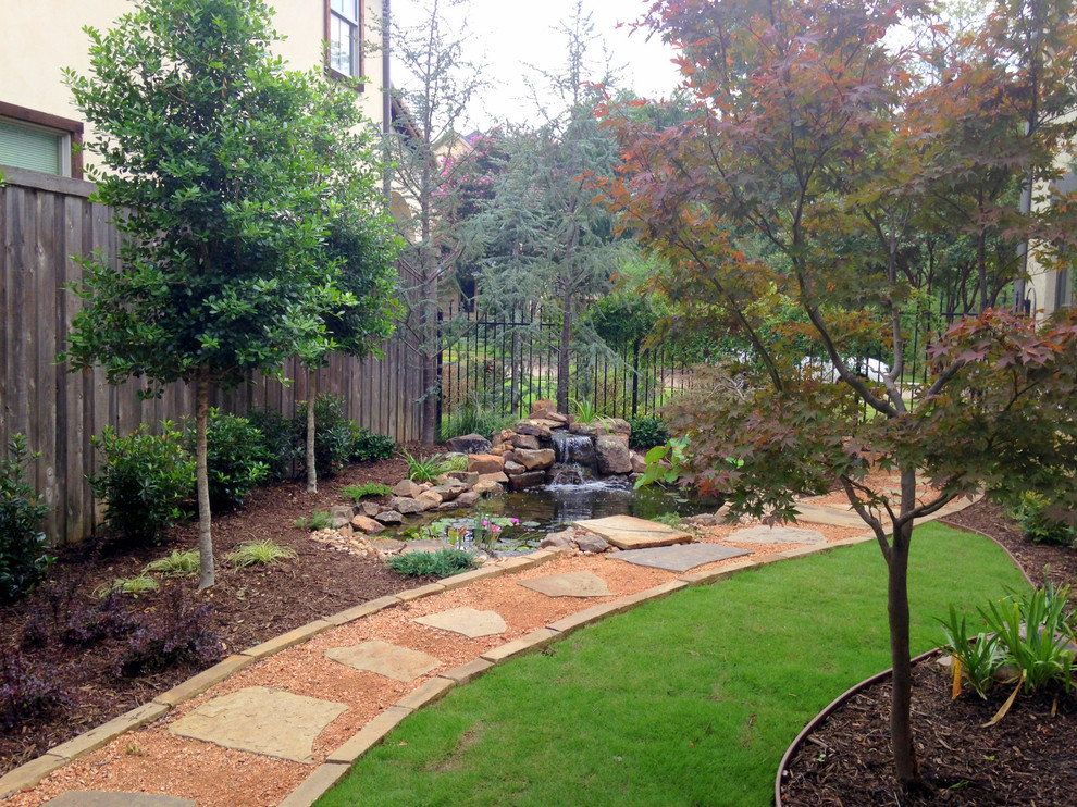 This is an example of a mid-sized transitional side yard partial sun garden in Dallas with a water feature and natural stone pavers.