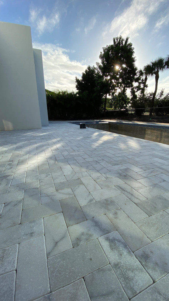 Design ideas for a mid-sized mediterranean backyard patio in Miami with natural stone pavers and no cover.