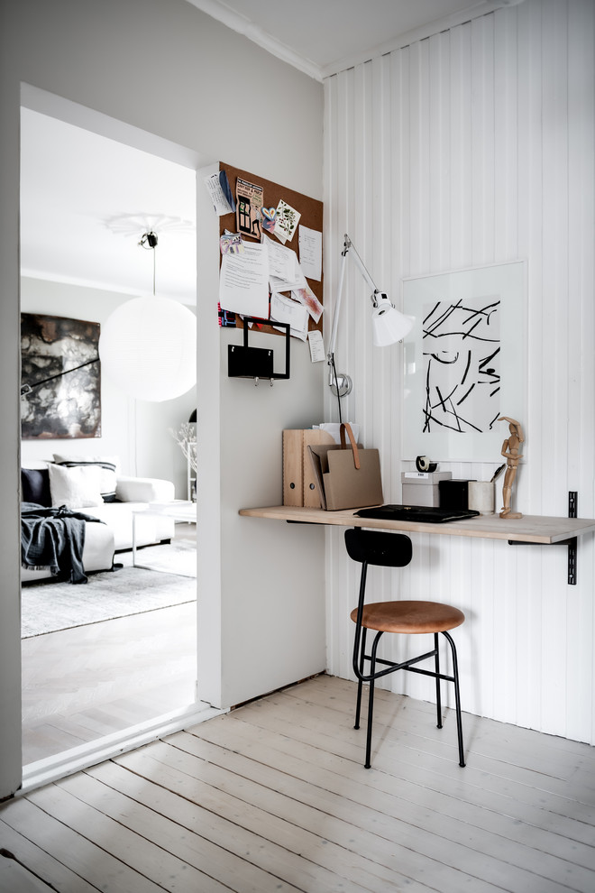 This is an example of a small modern study room in Gothenburg with white walls, light hardwood floors, no fireplace, a built-in desk and beige floor.