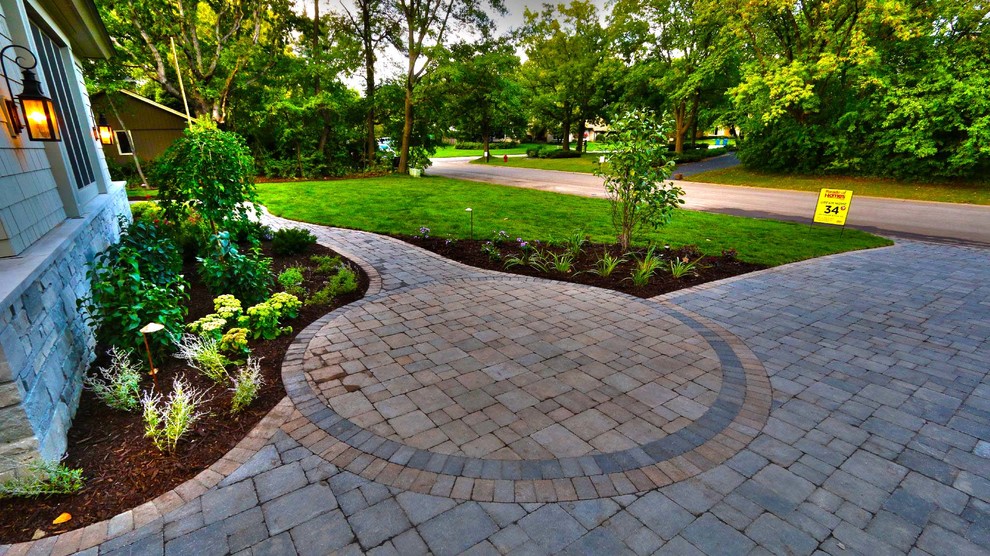 Photo of a mid-sized traditional front yard shaded driveway in Minneapolis with natural stone pavers.