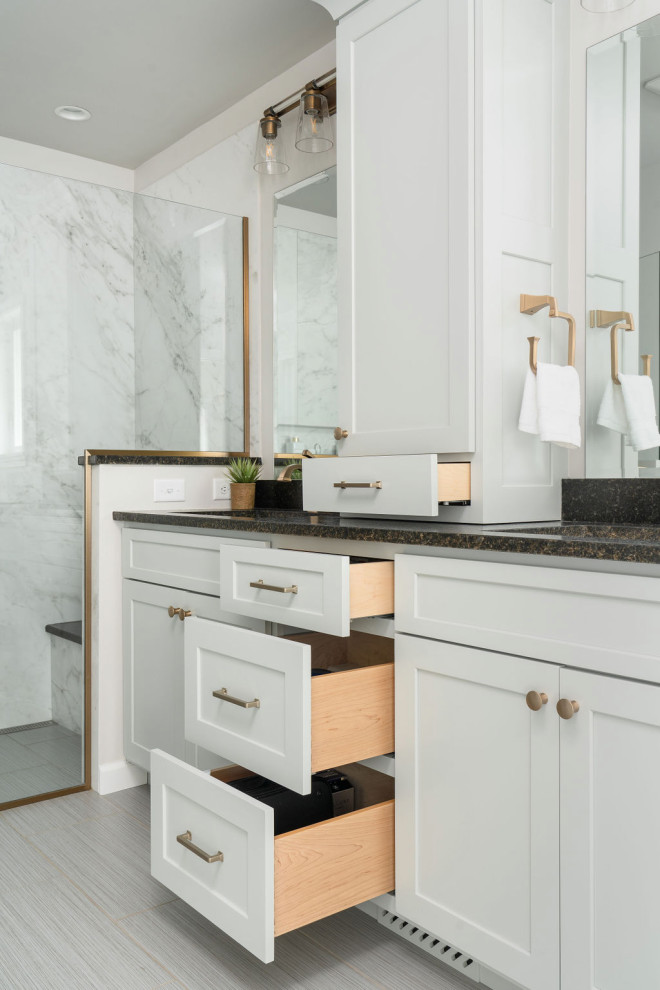 This is an example of a large transitional master bathroom in Columbus with shaker cabinets, grey cabinets, a curbless shower, white tile, porcelain tile, grey walls, porcelain floors, an undermount sink, granite benchtops, grey floor, a hinged shower door, black benchtops, a niche, a double vanity and a built-in vanity.