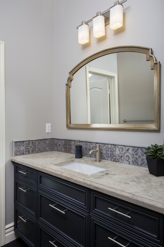 This is an example of a mid-sized mediterranean 3/4 bathroom in San Diego with recessed-panel cabinets, black cabinets, a drop-in tub, an alcove shower, a two-piece toilet, gray tile, porcelain tile, grey walls, porcelain floors, an undermount sink and engineered quartz benchtops.