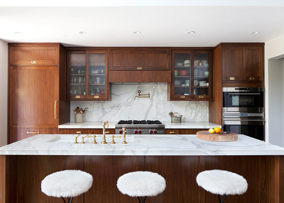 Photo of a contemporary kitchen in New York with with island, glass-front cabinets, medium wood cabinets, white splashback, stainless steel appliances and marble splashback.