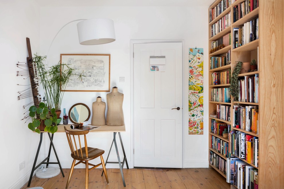 Design ideas for a small scandinavian home office in London with white walls, a freestanding desk, a library and medium hardwood floors.