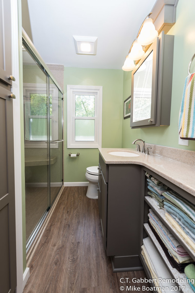 Small transitional 3/4 bathroom in Chicago with recessed-panel cabinets, grey cabinets, an alcove shower, multi-coloured walls, laminate floors, an integrated sink, onyx benchtops, brown floor and a sliding shower screen.