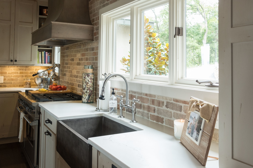Large transitional galley dark wood floor and brown floor open concept kitchen photo with a farmhouse sink, shaker cabinets, quartz countertops, brown backsplash, brick backsplash, stainless steel appliances and an island