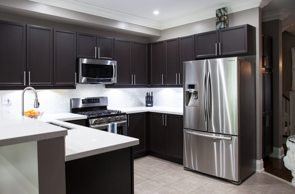 Photo of a mid-sized contemporary u-shaped eat-in kitchen in Toronto with an undermount sink, shaker cabinets, brown cabinets, quartz benchtops, white splashback, glass tile splashback, stainless steel appliances, porcelain floors and a peninsula.