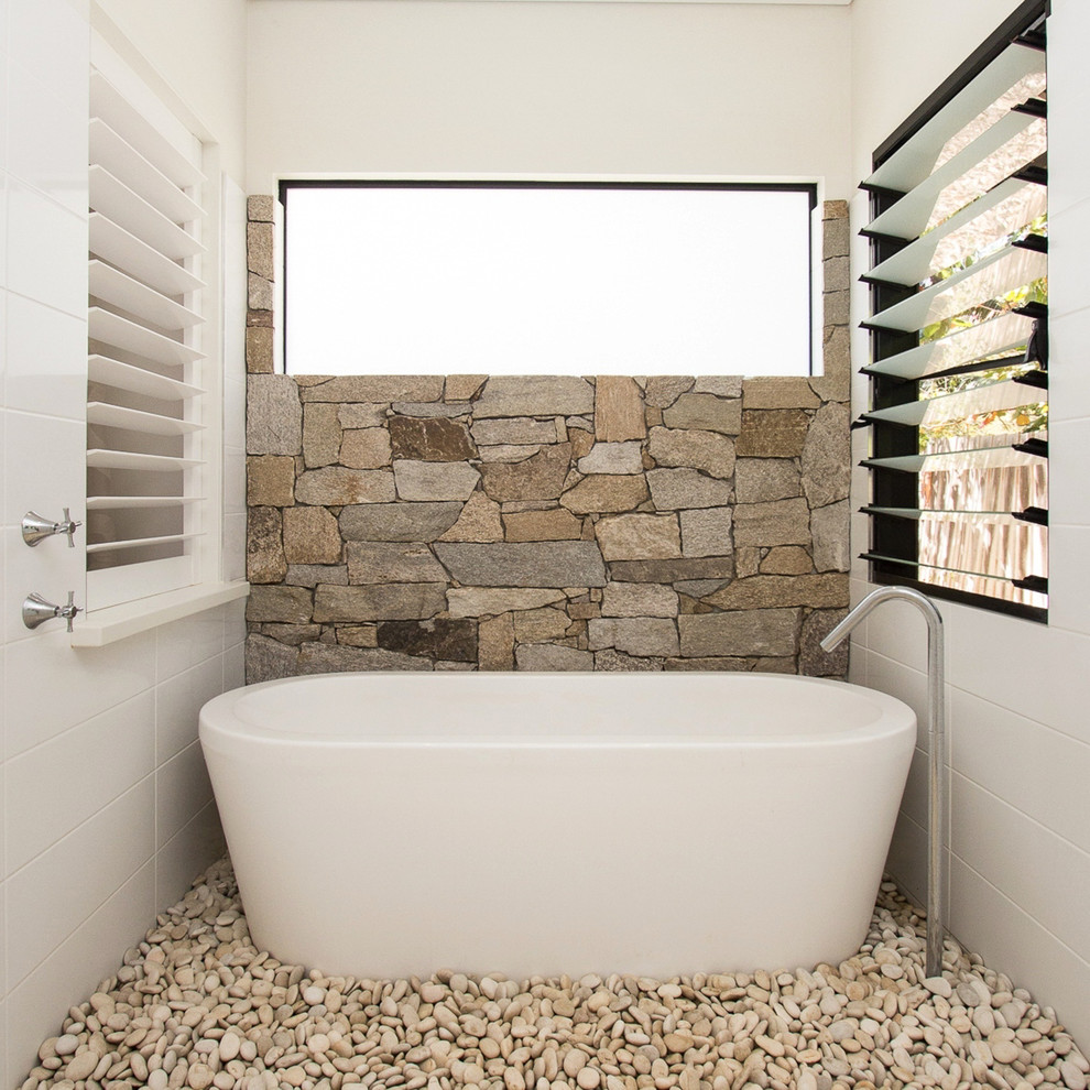 Mid-sized country master bathroom in Dunedin with a freestanding tub, beige tile, stone tile and white walls.