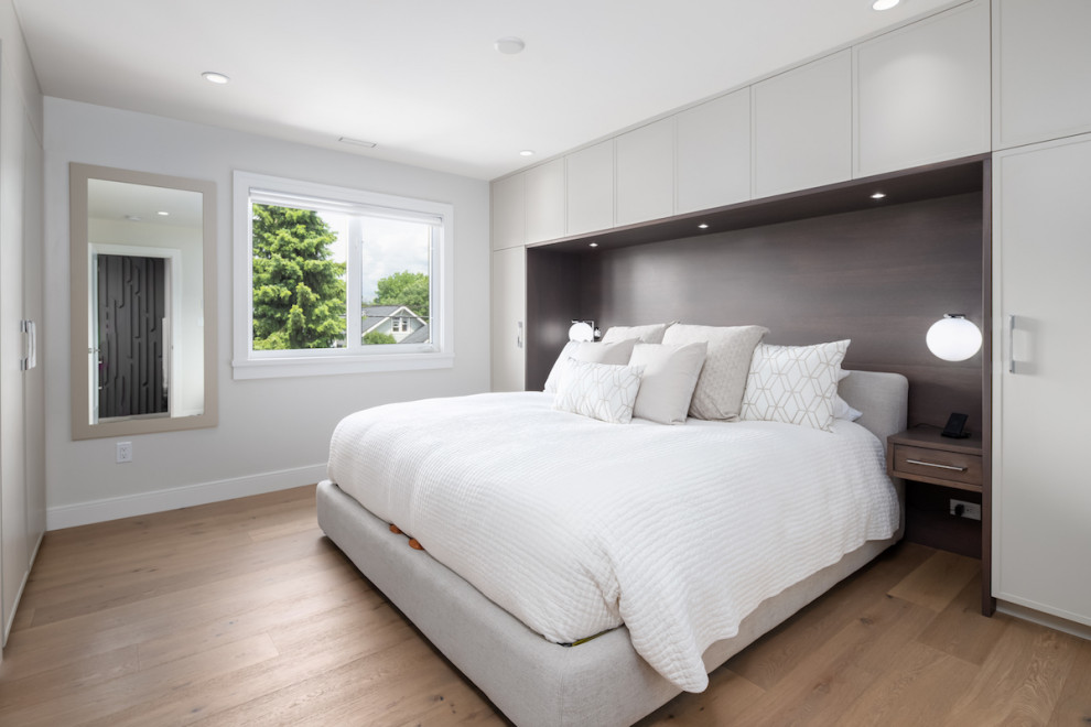 Example of a mid-sized trendy master light wood floor, beige floor and wood wall bedroom design in Vancouver with white walls
