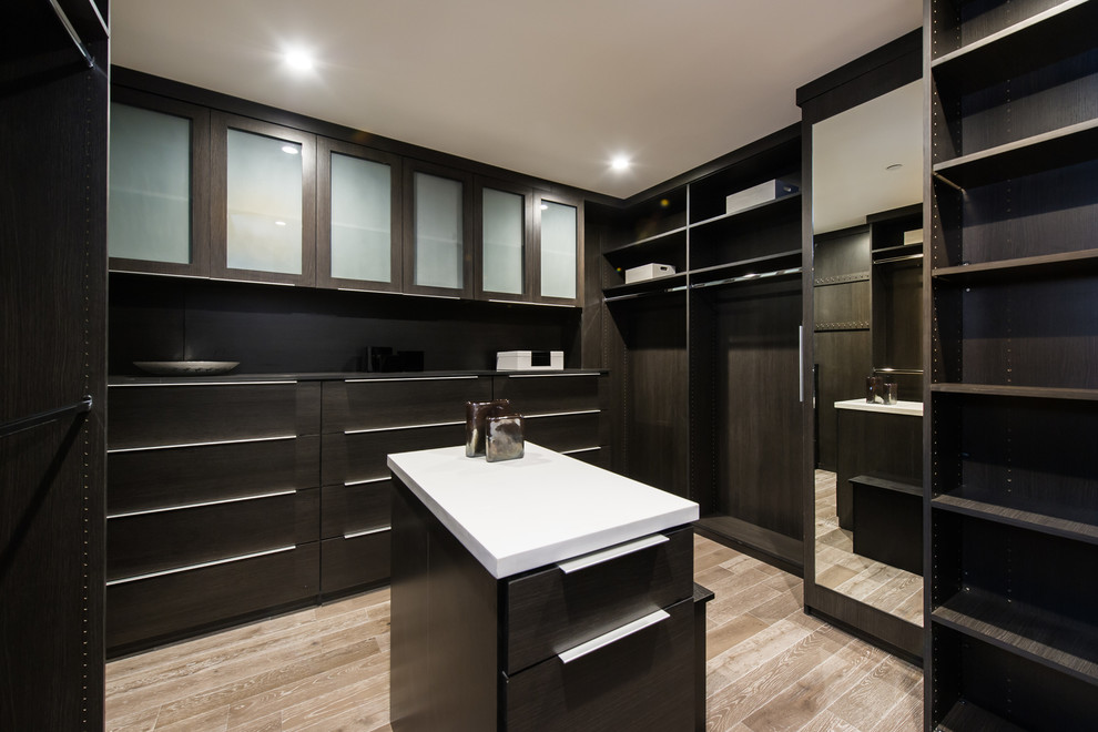 Photo of a large contemporary gender-neutral walk-in wardrobe in Los Angeles with flat-panel cabinets, dark wood cabinets and medium hardwood floors.