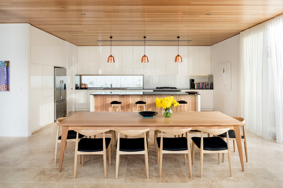 This is an example of a scandinavian l-shaped eat-in kitchen in Perth with flat-panel cabinets, white cabinets, marble benchtops, grey splashback, stainless steel appliances, travertine floors and with island.