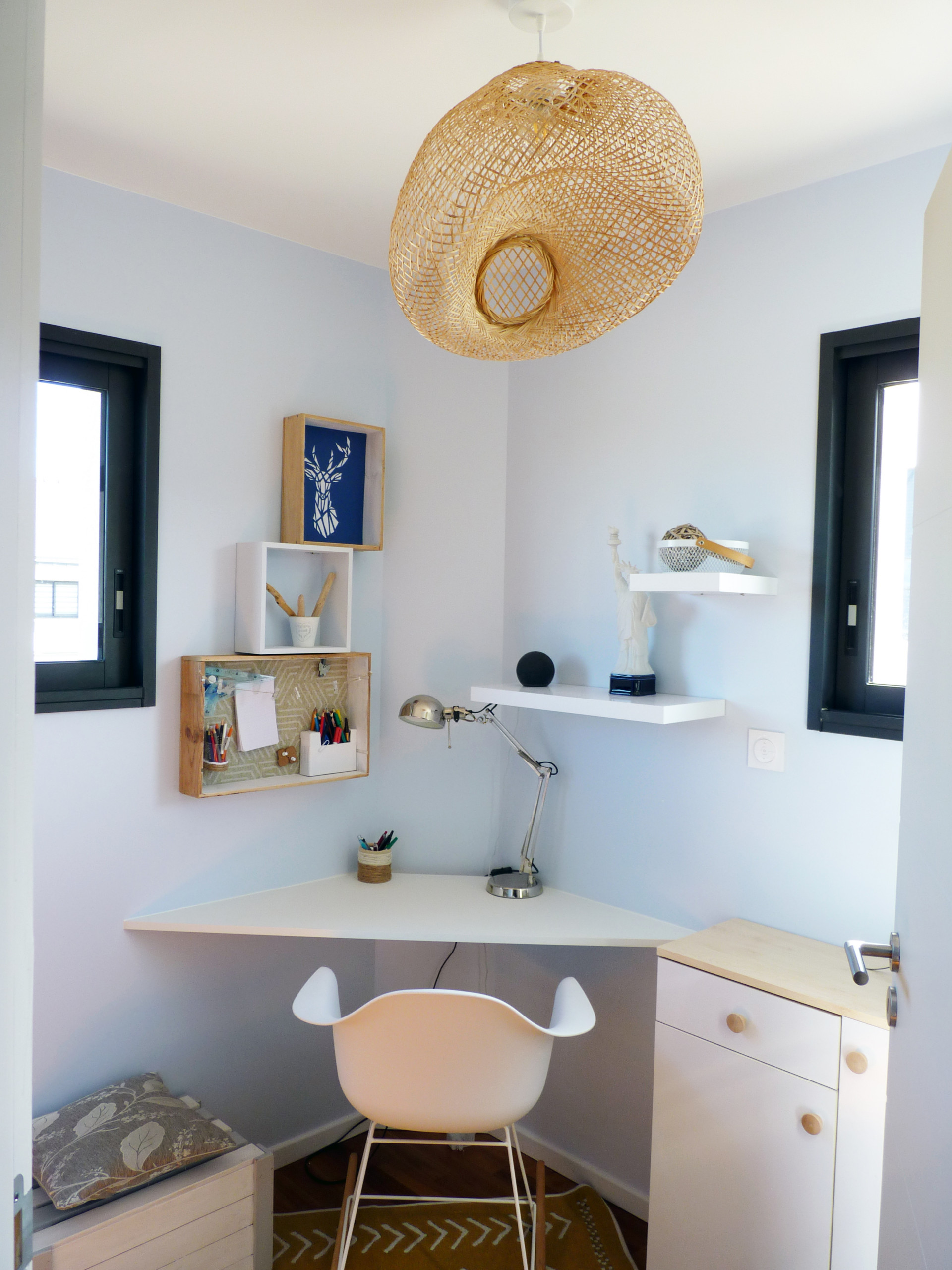 Bureau d'angle dans la chambre pour utiliser au mieux tout l'espace disponible. Luminaire en osier central pour apporter de la lumière dans toute la pièce.