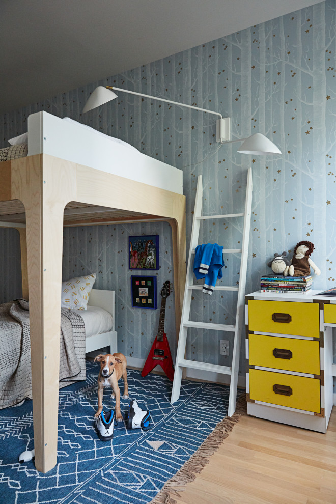 Mid-sized scandinavian gender-neutral kids' bedroom in New York with blue walls, light hardwood floors, blue floor and wallpaper for kids 4-10 years old.