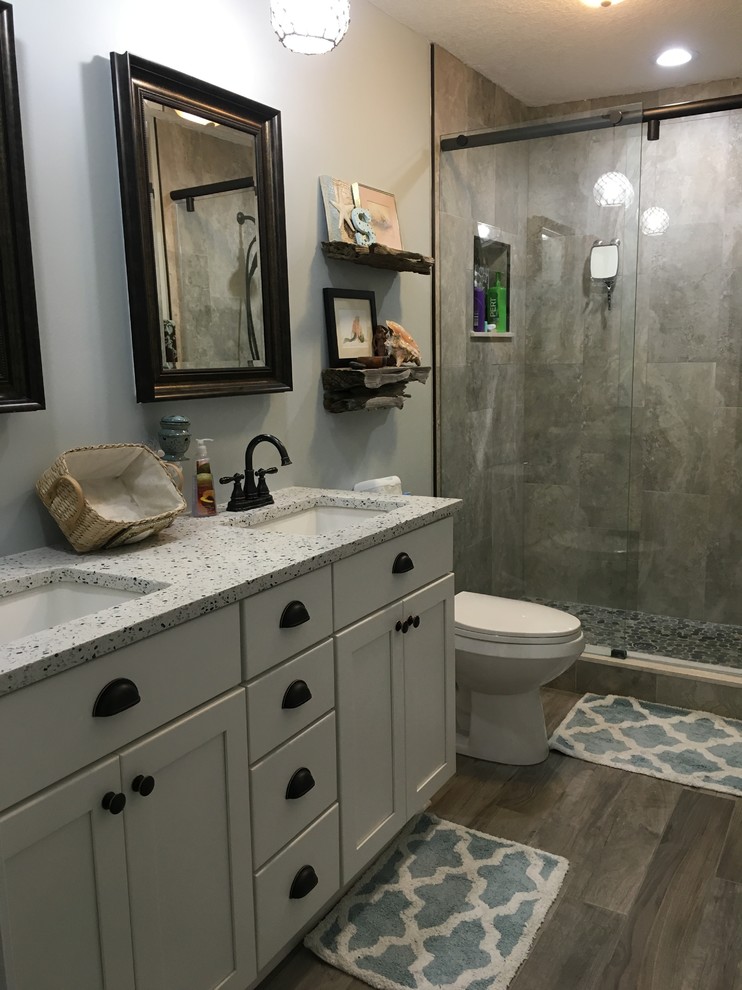 Design ideas for a small beach style 3/4 bathroom in Jacksonville with white cabinets, an open shower, an undermount sink, granite benchtops, shaker cabinets, a two-piece toilet, beige tile, stone tile, white walls and light hardwood floors.