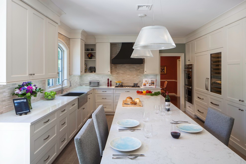 Traditional l-shaped separate kitchen in Philadelphia with stone tile splashback, recessed-panel cabinets, panelled appliances and a farmhouse sink.