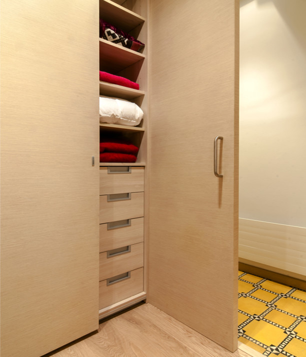 Design ideas for a small modern gender-neutral built-in wardrobe in Barcelona with flat-panel cabinets and light wood cabinets.