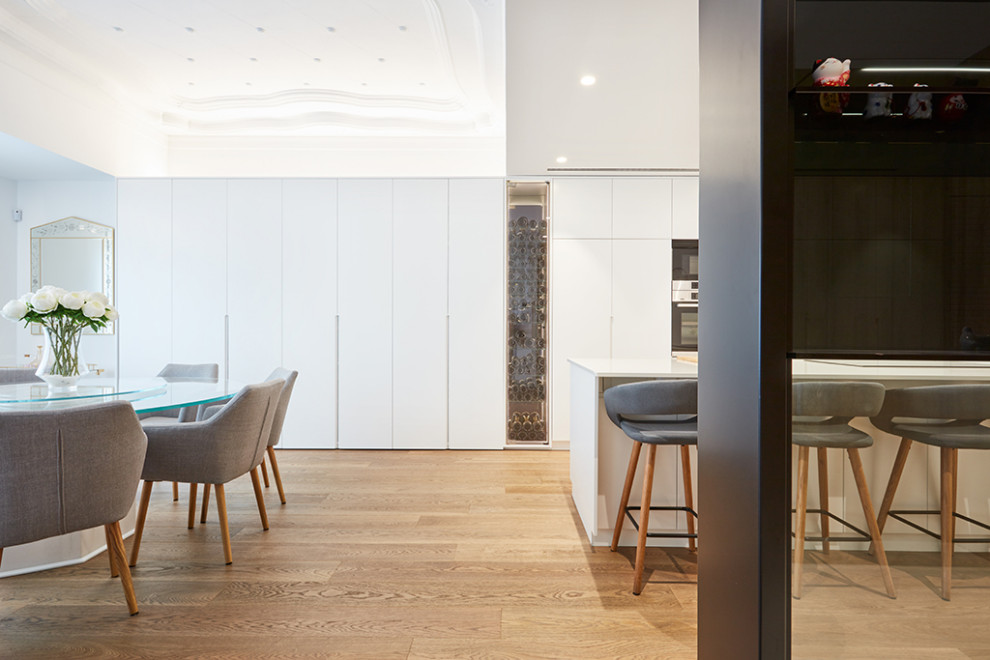 Ejemplo de comedor de cocina contemporáneo grande sin chimenea con paredes blancas, suelo de madera en tonos medios y suelo beige