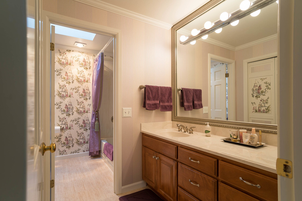 This is an example of a mid-sized traditional bathroom in Seattle with raised-panel cabinets, medium wood cabinets, an alcove tub, a shower/bathtub combo, pink walls and an integrated sink.