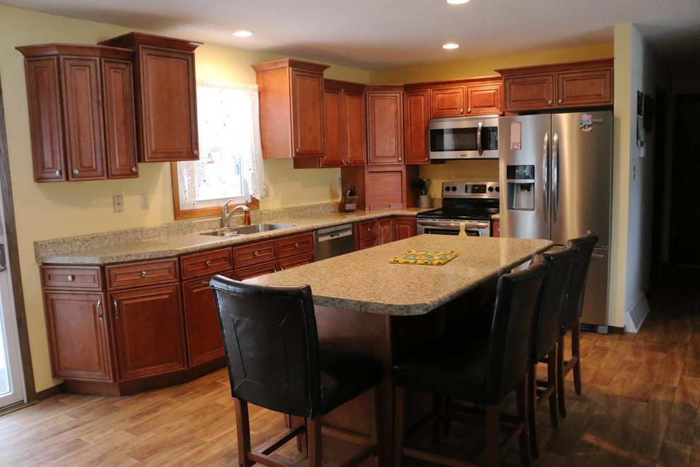 Example of a mid-sized transitional l-shaped medium tone wood floor enclosed kitchen design with an undermount sink, raised-panel cabinets, medium tone wood cabinets, granite countertops, beige backsplash, mosaic tile backsplash, stainless steel appliances and an island