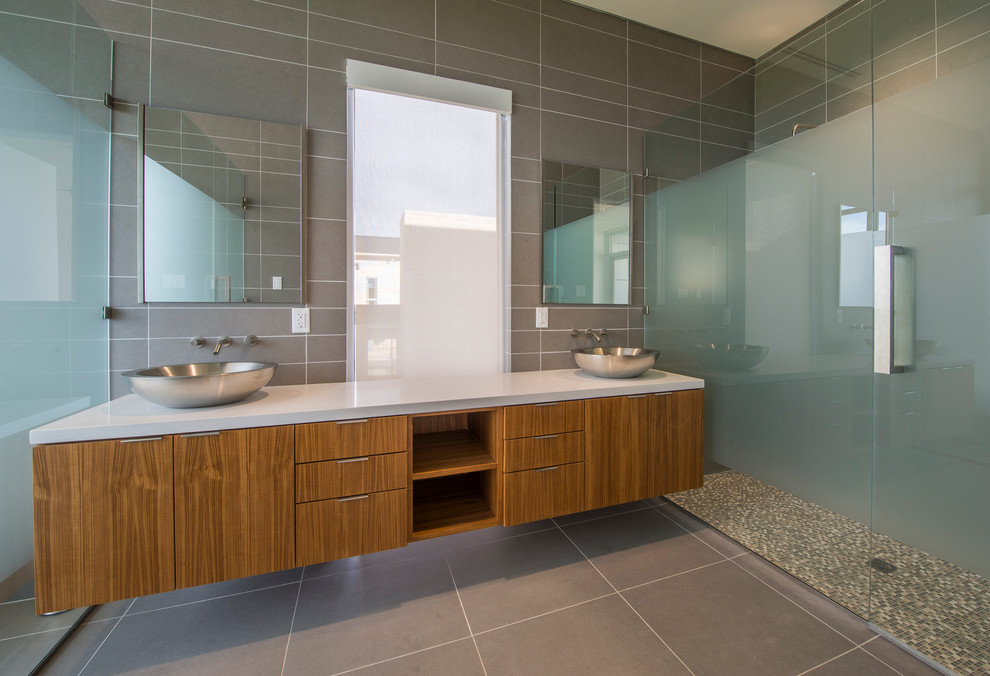 Contemporary bathroom in Dallas with flat-panel cabinets, medium wood cabinets, an alcove shower, gray tile, a vessel sink and a hinged shower door.