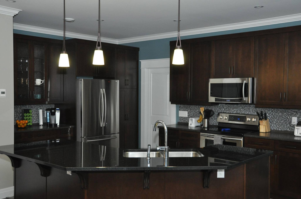 Kitchen - mid-sized l-shaped laminate floor kitchen idea with an undermount sink, dark wood cabinets, multicolored backsplash, mosaic tile backsplash, stainless steel appliances, an island, recessed-panel cabinets, quartzite countertops and black countertops