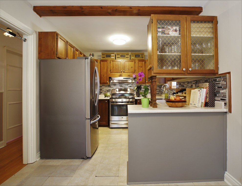 Inspiration for a mid-sized transitional u-shaped vinyl floor eat-in kitchen remodel in Toronto with a double-bowl sink, shaker cabinets, medium tone wood cabinets, laminate countertops, multicolored backsplash, mosaic tile backsplash, stainless steel appliances and a peninsula