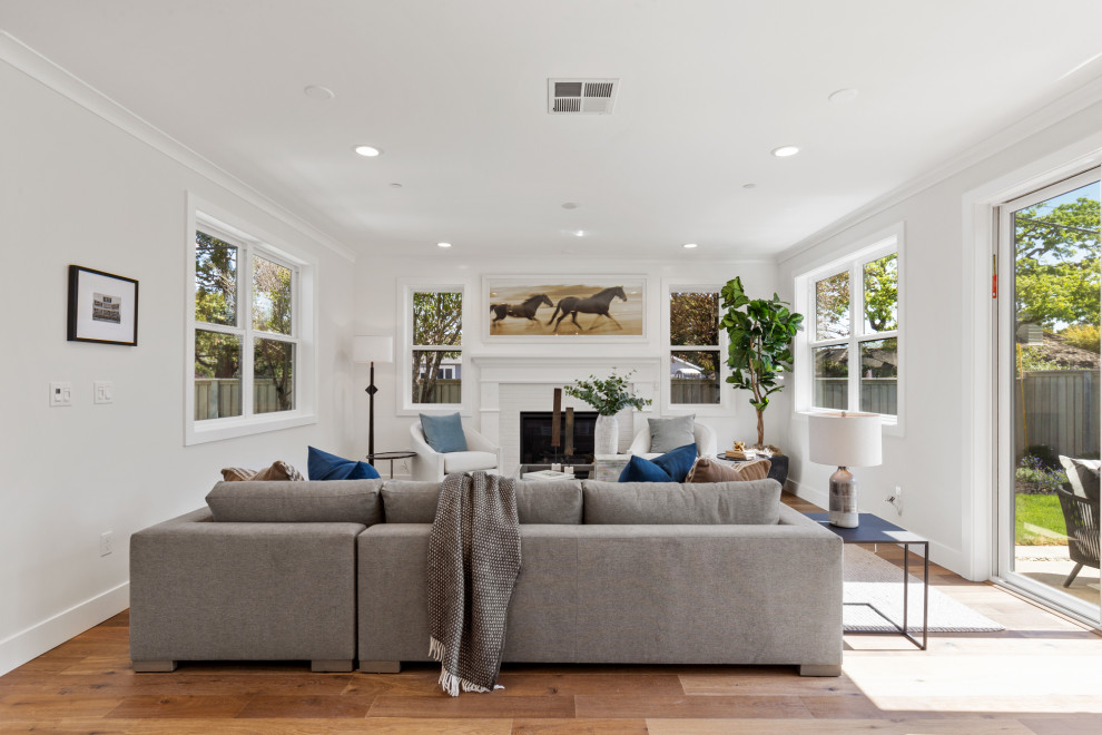 Photo of a rural open plan living room in San Francisco with white walls, medium hardwood flooring, a standard fireplace and brown floors.