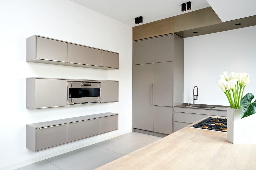 Large contemporary single-wall eat-in kitchen in Hamburg with an undermount sink, flat-panel cabinets, grey cabinets, solid surface benchtops, white splashback, panelled appliances, concrete floors and a peninsula.