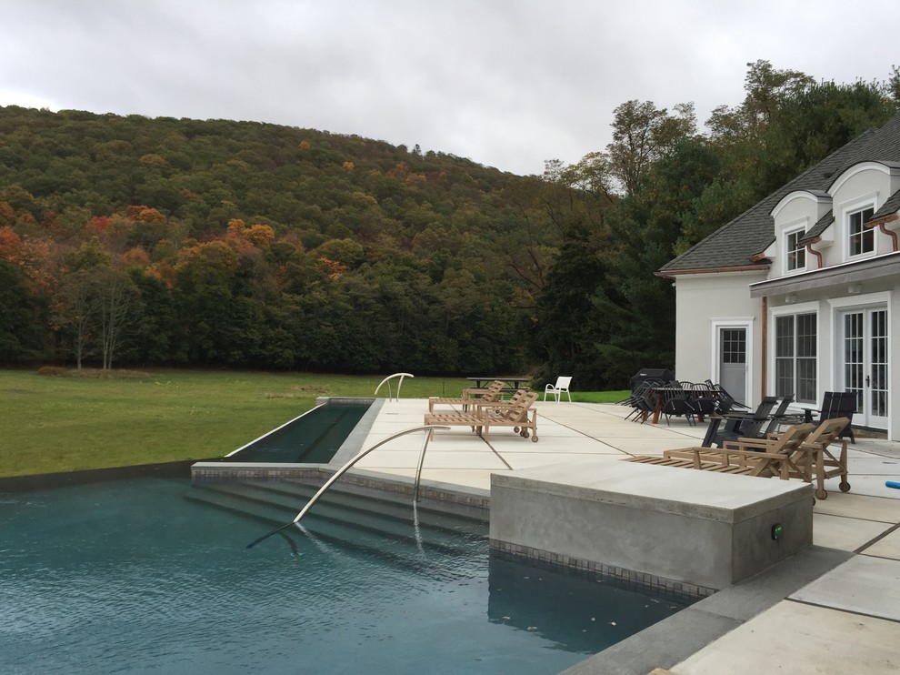 Inspiration for a large country backyard l-shaped lap pool in New York with concrete slab.