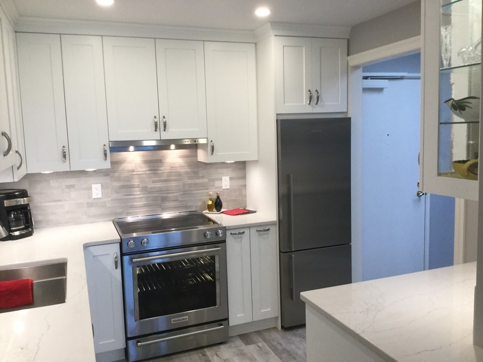 This is an example of a small transitional l-shaped open plan kitchen in Vancouver with a double-bowl sink, recessed-panel cabinets, white cabinets, marble benchtops, grey splashback, ceramic splashback, stainless steel appliances, porcelain floors, no island and grey floor.