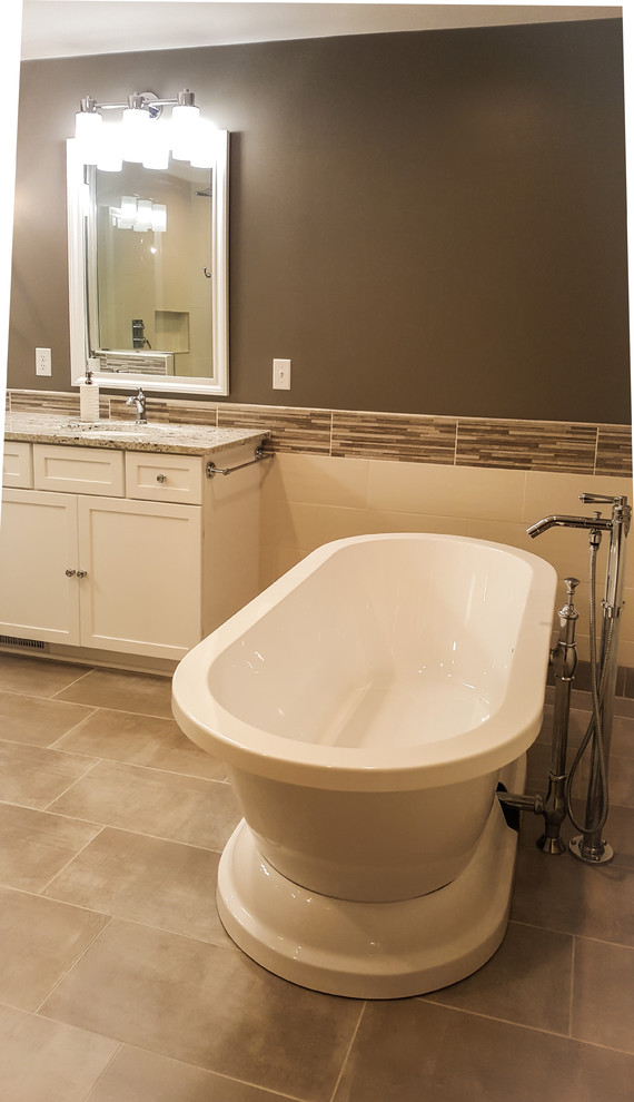 Large transitional master multicolored tile and ceramic tile porcelain tile and gray floor freestanding bathtub photo with shaker cabinets, white cabinets, a two-piece toilet, gray walls, an undermount sink, granite countertops and a hinged shower door