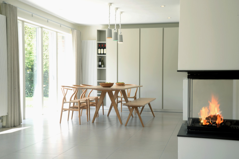 Photo of a contemporary dining room in Sussex with grey walls and a corner fireplace.