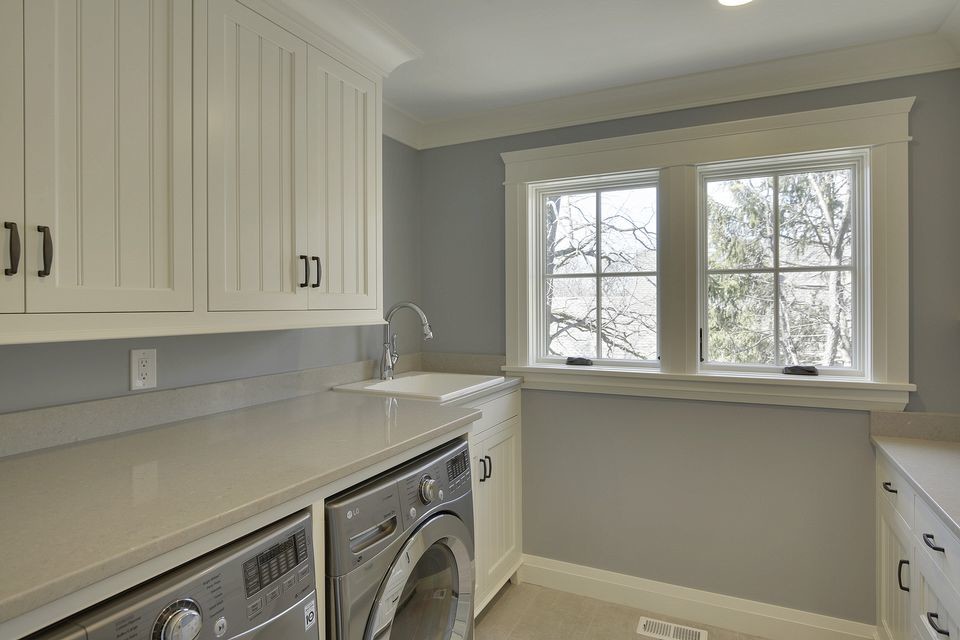 Mid-sized transitional galley dedicated laundry room in Minneapolis with a drop-in sink, shaker cabinets, white cabinets, quartz benchtops, grey walls, porcelain floors and a side-by-side washer and dryer.