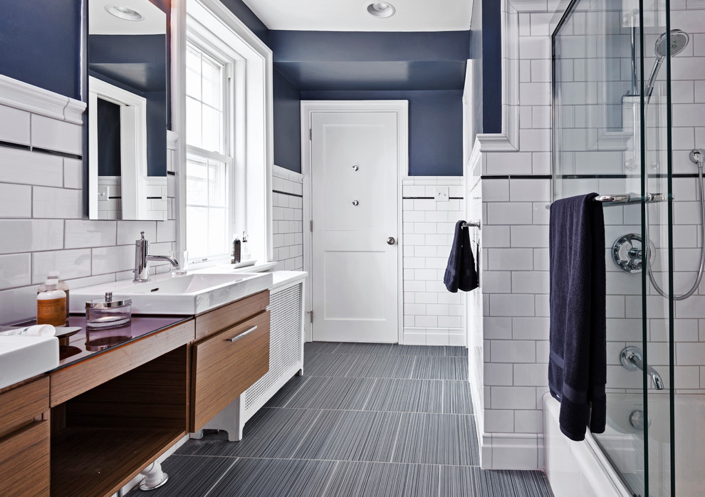 Alcove bathtub - mid-sized transitional white tile and ceramic tile porcelain tile alcove bathtub idea in Philadelphia with a wall-mount sink, flat-panel cabinets, medium tone wood cabinets, glass countertops, a one-piece toilet and blue walls